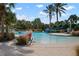 A community pool with a waterslide, zero entry access, and surrounded by palm trees and flowering shrubs at 11435 Fort Lauderdale Pl, Venice, FL 34293