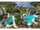 Scenic aerial view of community pools, a waterslide, and a serene lake with lush green surroundings at 11435 Fort Lauderdale Pl, Venice, FL 34293