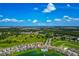 Aerial view of home with a lush green community, pool, lake, and scenic surroundings, highlighted by blue skies at 12613 Oak Hill Way, Parrish, FL 34219