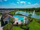Aerial view of community pool and lake with fountain, and blue lounge chairs by the poolside at 12613 Oak Hill Way, Parrish, FL 34219