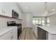Well-lit kitchen features stainless steel appliances, quartz countertops, white cabinetry, wood flooring and a center island at 12613 Oak Hill Way, Parrish, FL 34219