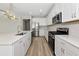 A modern kitchen featuring white cabinets, stainless steel appliances, quartz countertops, wood flooring, and recessed lighting at 12613 Oak Hill Way, Parrish, FL 34219