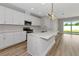 Bright kitchen boasts white cabinets, stainless steel appliances, quartz countertops, and an island with a modern pendant light at 12613 Oak Hill Way, Parrish, FL 34219