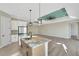Bright open floor plan features an island with a sink, modern lighting, and stainless steel appliances at 144 Spring Dr, Rotonda West, FL 33947