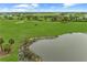 Aerial view of a well-manicured golf course with pond and green, under a beautiful blue sky at 15707 Sacile Ln, Bradenton, FL 34211