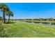 Scenic backyard view of the lake and surrounding community, framed by lush greenery and palm trees at 15707 Sacile Ln, Bradenton, FL 34211