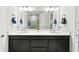 Modern bathroom featuring double sinks, sleek black cabinetry, and a large mirror reflecting a glass-enclosed shower at 15707 Sacile Ln, Bradenton, FL 34211