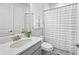 Clean bathroom with a single sink, white vanity, and a shower-tub combo with a stylish striped curtain at 15707 Sacile Ln, Bradenton, FL 34211