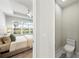 Bright bedroom showcasing a cozy bed, a large window with backyard views, and an attached half bathroom at 15707 Sacile Ln, Bradenton, FL 34211