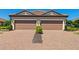 Home featuring a two-car garage, brick paved driveway and landscaping at 15707 Sacile Ln, Bradenton, FL 34211
