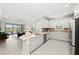 Bright, open kitchen with white cabinetry, tile backsplash, stainless appliances, and view of the living room at 15707 Sacile Ln, Bradenton, FL 34211