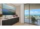 Stylish bar area with wine fridge, art display, and balcony access with beautiful ocean views at 1591 Gulf Of Mexico Dr # 511, Longboat Key, FL 34228