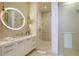 Modern bathroom featuring a sleek vanity with a circular mirror and a glass-enclosed shower with unique tiling at 1591 Gulf Of Mexico Dr # 511, Longboat Key, FL 34228
