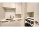 Efficient laundry room with white cabinets, a sink, and a front-load washing machine at 1591 Gulf Of Mexico Dr # 511, Longboat Key, FL 34228