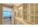 Bathroom with a stylish vanity, glass-enclosed cabinet, and a glimpse of the bedroom and ocean view at 19 Whispering Sands Dr # 805, Sarasota, FL 34242
