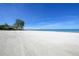 Expansive white sandy beach with clear ocean waters and a few people in the distance under a bright, sunny sky at 19 Whispering Sands Dr # 805, Sarasota, FL 34242