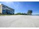Wide, sandy beach with multi-story buildings and lush vegetation under a clear, blue sky at 19 Whispering Sands Dr # 805, Sarasota, FL 34242