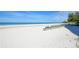 Chairs on a white, sandy beach with gentle waves lapping the shore under a clear, blue sky at 19 Whispering Sands Dr # 805, Sarasota, FL 34242