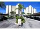 Exterior shot of a white condominium building, showcasing lush landscaping and covered parking at 19 Whispering Sands Dr # 805, Sarasota, FL 34242