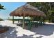 Beach picnic area with a large shaded hut over a table and benches on a sandy area at 19 Whispering Sands Dr # 805, Sarasota, FL 34242