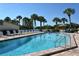 Community pool surrounded by lounge chairs and palm trees with open swim area at 19 Whispering Sands Dr # 805, Sarasota, FL 34242