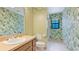 Bright bathroom featuring tropical wallpaper, large mirror, and tiled flooring at 2061 Misty Sunrise Trl, Sarasota, FL 34240