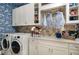 Convenient laundry room with modern appliances, ample storage, and stylish nautical wallpaper at 21225 Wacissa Dr, Venice, FL 34293