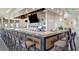 A modern bar area with a marble countertop, stools, liquor shelving, and a mounted television at 23233 Banbury Way # 302, Venice, FL 34293