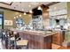 A bar area with a wooden bar, stools, shelves of liquor, and mounted television at 23233 Banbury Way # 302, Venice, FL 34293