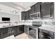 Bright kitchen featuring stainless steel appliances, granite counters, mosaic backsplash, and dark cabinetry at 23233 Banbury Way # 302, Venice, FL 34293