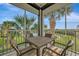 Screened in porch features a table with 4 chairs with view of tropical trees and lawn at 23233 Banbury Way # 302, Venice, FL 34293