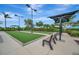 An outdoor game area with lush artificial turf, shaded benches, and well maintained landscaping at 23233 Banbury Way # 302, Venice, FL 34293