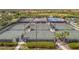 Aerial view of multiple fenced tennis courts with shelters, nestled in a lush, landscaped community at 23233 Banbury Way # 302, Venice, FL 34293