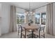 Dining room features a round table, modern chandelier, and large windows with elegant window treatments at 2578 Wild Cherry Path, Sarasota, FL 34240