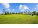 Community dog park with lush green grass, mature trees, bench seating, and a convenient pet waste station at 2578 Wild Cherry Path, Sarasota, FL 34240