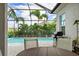 Screened patio featuring a built-in grill, outdoor seating, and stunning views of the private pool and lush landscaping at 2578 Wild Cherry Path, Sarasota, FL 34240