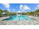 Community pool and clubhouse surrounded by palms and lounge chairs under sunny skies at 2578 Wild Cherry Path, Sarasota, FL 34240