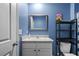Bright bathroom with grey countertop, framed mirror, and black storage shelving at 2721 Greenleaf Ter, Parrish, FL 34219