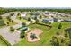 Aerial view of a community playground, surrounded by green spaces, homes, and a pond with a fountain at 2721 Greenleaf Ter, Parrish, FL 34219