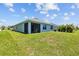 View of the home's back exterior featuring a screened lanai and lush green lawn at 2721 Greenleaf Ter, Parrish, FL 34219