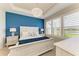 Bright bedroom featuring a blue accent wall, large windows with shutters, and a white furniture set at 3027 Formia Ct, Lakewood Ranch, FL 34211