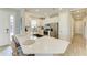 Modern, all-white kitchen featuring a center island with bar seating, stainless steel appliances and tile floors at 3027 Formia Ct, Lakewood Ranch, FL 34211