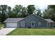 Side exterior of home with two-car garage, dark gray siding, and a well-maintained lawn at 3287 Rackley Rd, Brooksville, FL 34604
