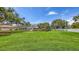 Expansive green backyard with mature trees, landscaping, and a screened in lanai at 3764 Oak Grove Dr, Sarasota, FL 34243