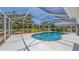 Inviting screened-in pool area with ample deck space, surrounded by lush landscaping and a clear blue sky at 3764 Oak Grove Dr, Sarasota, FL 34243