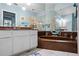 Well-lit bathroom with an inset bathtub and large mirrors reflecting the space at 4203 Carriage Dr # 27, Sarasota, FL 34241
