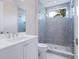 Modern bathroom featuring a vanity, shower with blue tile, and a large window at 430 Pheasant Way, Sarasota, FL 34236