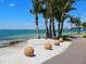 Scenic beach view featuring palm trees, tranquil turquoise waters, and decorative stone orbs along the shoreline at 430 Pheasant Way, Sarasota, FL 34236