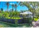 Home exterior showcasing front yard, mature palms, privacy fencing, and meticulous landscaping at 4505 Camino Real, Sarasota, FL 34231