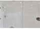 Modern shower featuring large white subway tiles, glass door, and recessed niche for toiletries at 4505 Camino Real, Sarasota, FL 34231